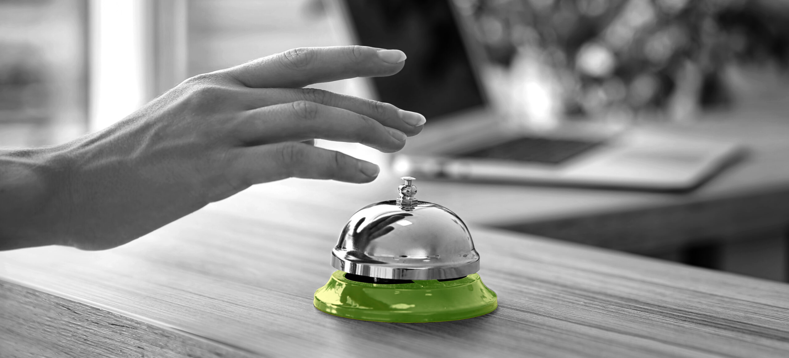 Woman ringing service bell on reception desk in hotel, closeup